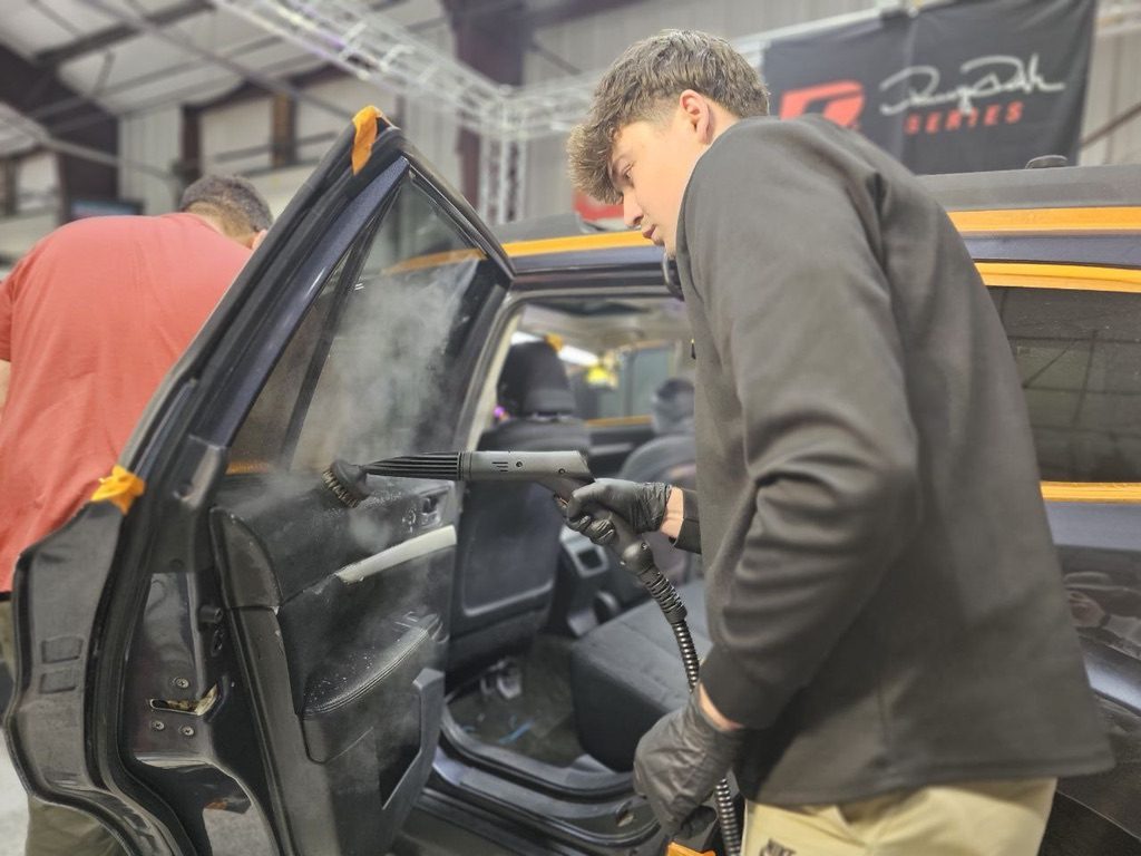 Steam cleaning an interior door panel at Detailing Success training, Blue Badge Customs mobile detailing in Lawrence, Kansas